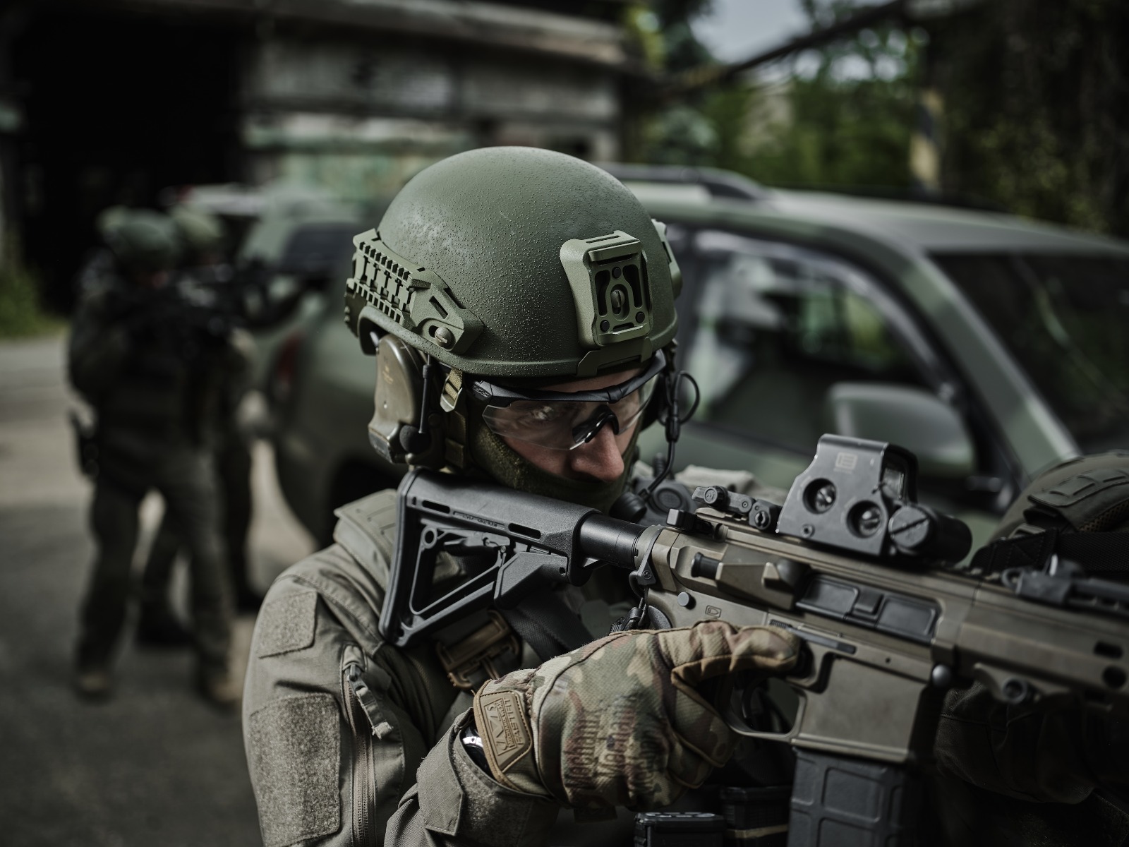 Operator wearing an olive green CES ballistic helmet with side rails and NVG shroud